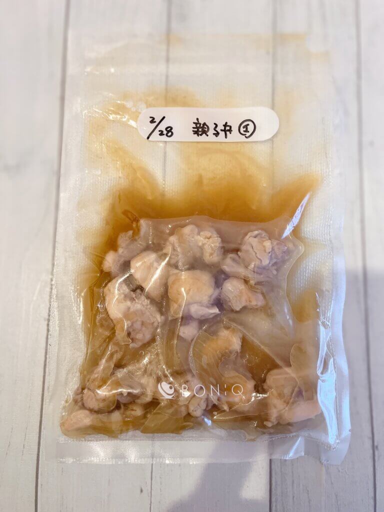 親子丼の具を真空パックする前の状態。鶏肉と玉ねぎを煮たものを袋に入れている様子。