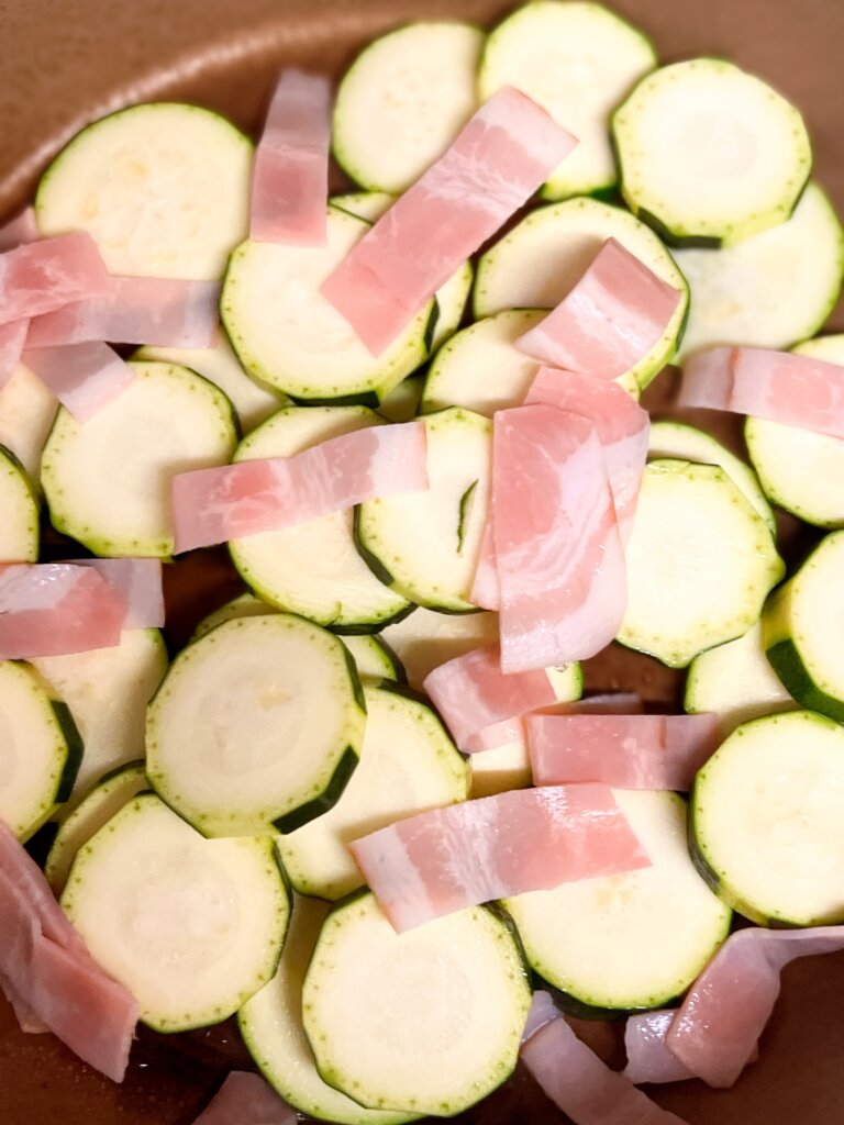 ズッキーニとベーコンをフライパンに並べてる