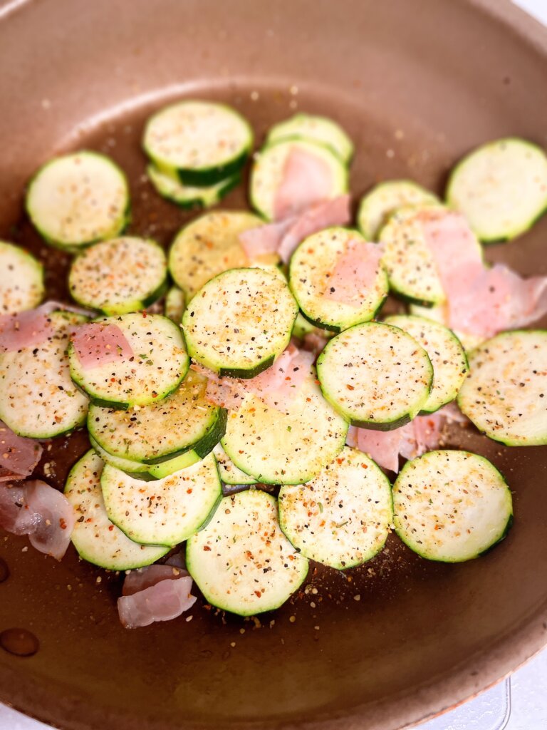 ズッキーニとベーコンにスパイスをふって仕上げる